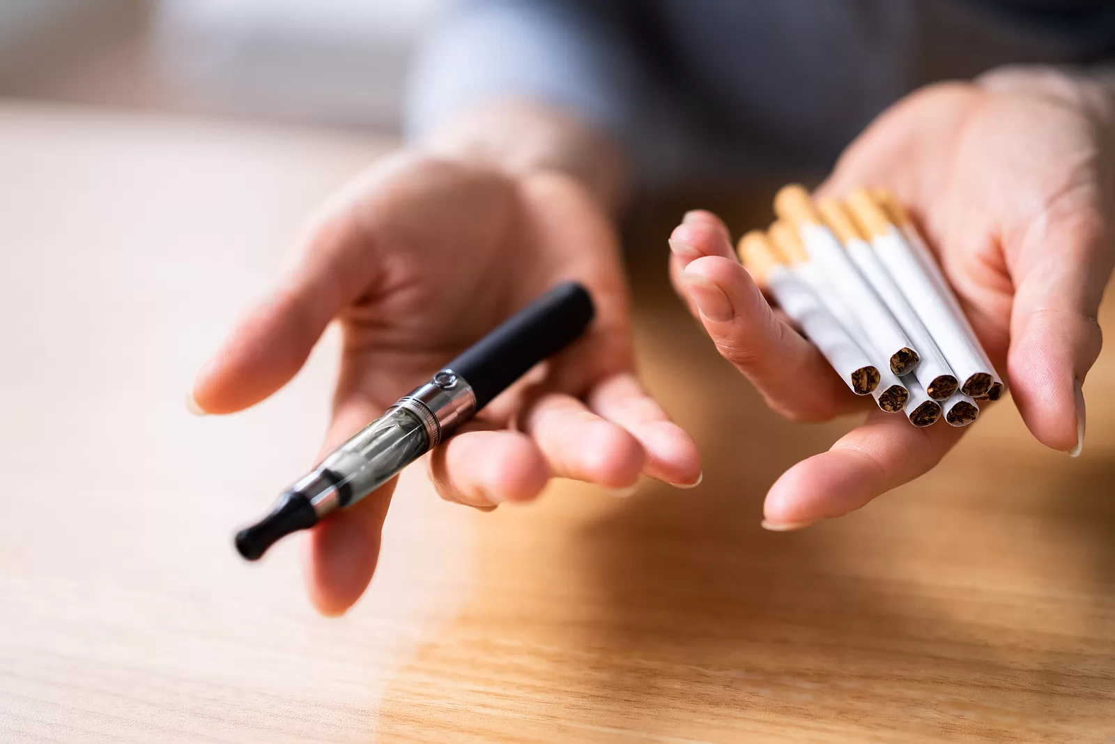 Woman's Hand Holding Vape And Tobacco Cigarettes